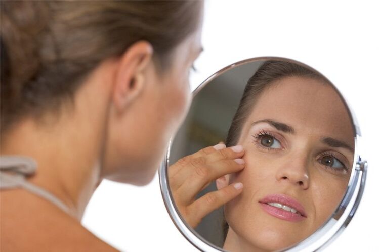 the girl looks at herself in the mirror before skin rejuvenation